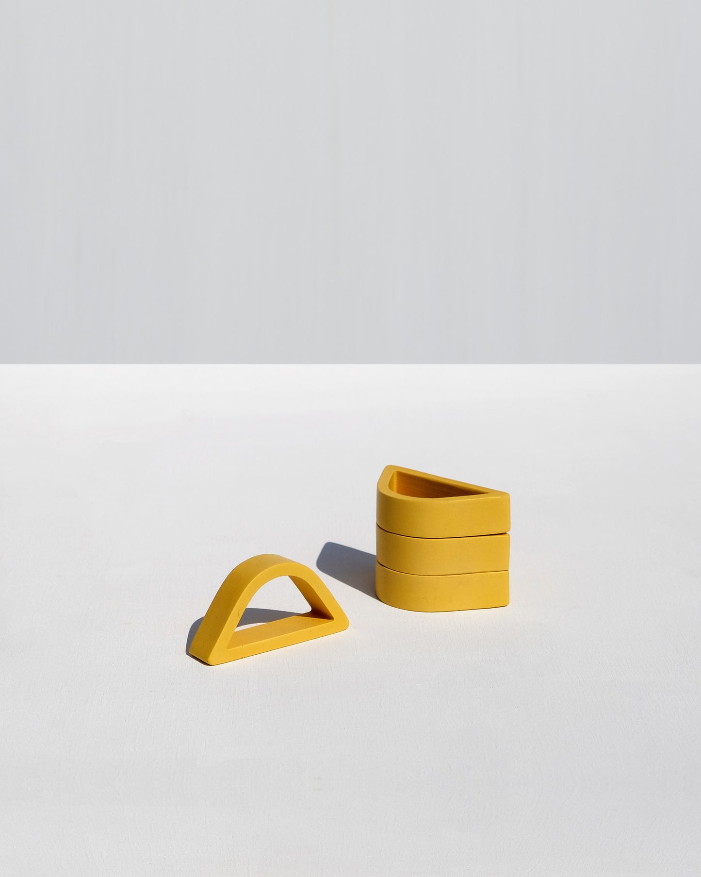 Set of four yellow arched napkin rings handcrafted by Alkaline Shop in South Africa, perfect for elegant table settings and modern dining decor